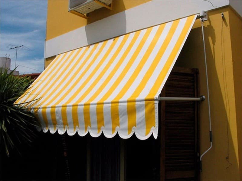 Toldo de lona enrollable a rayas instalado sobre fachada